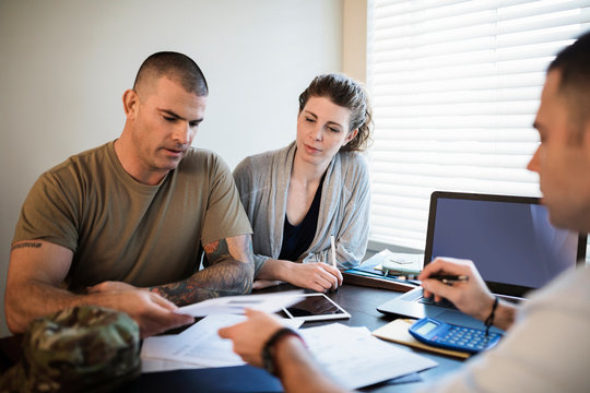 Military Couple Meeting With Financial Advisor At Home