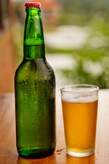 Bottle and glass of beer on a wooden table.