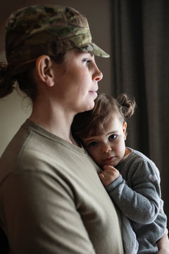 Portrait soldier mother holding preschool daughter