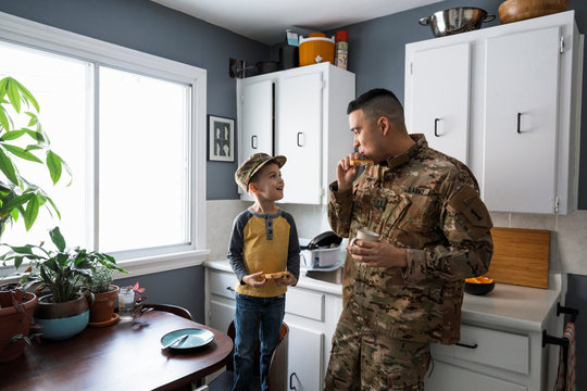 Military father and son eating breakfast and talking in kitchen