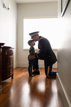 Military officer in dress uniform father kissing son at window