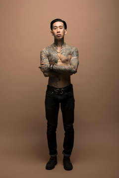 Portrait Of Confident Young Man With Chest And Arm Tattoos