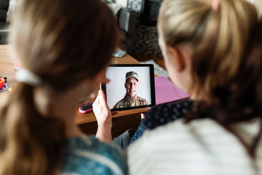 Soldier father on digital tablet video chatting with daughters