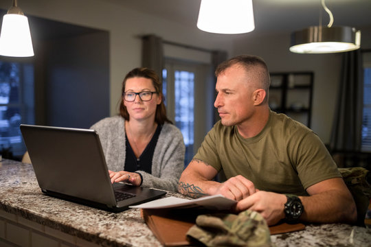 Military couple using laptop at kitchen counter