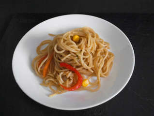 spaghetti on a white plate on a black background