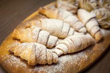 Close up of delicious croissants and pastries with apples, on a wooden Board in a cafe