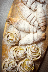 Close up of delicious croissants and pastries with apples, on a wooden Board in a cafe