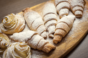 Close up of delicious croissants and pastries with apples, on a wooden Board in a cafe