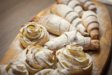 Close up of delicious croissants and pastries with apples, on a wooden Board in a cafe