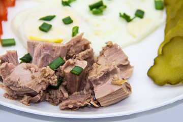 Delicious fresh tuna with eggs at the morning. Healthy and diet breakfast with tuna, eggs and vegetables on the white plate.