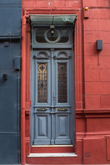 Obraz premium old textural door in grey and fragment of house facade in red