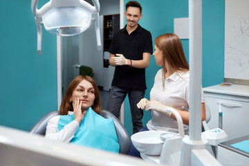 Cosmetic dentistry. Male doctor with his assistant inspecting woman patient teeth. Concept of...