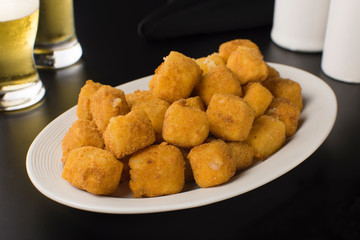 Traditional Brazilian pub food provolone cheese in breadcrumbs called provolone a milanesa black pub table