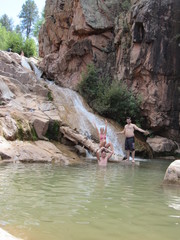 The Ellison Creek waterfall with tourists and locals sitting and swimming at the Water Wheel Falls hiking trail