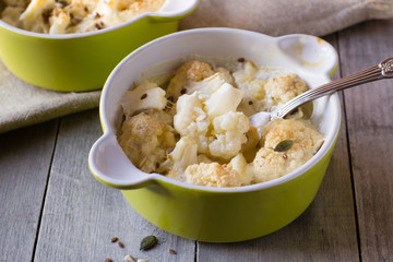 Baked cauliflower with cream on wooden table
