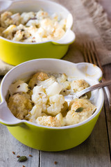Baked cauliflower with cream on wooden table
