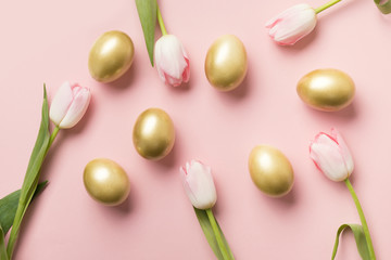 Easter golden eggs and pink tulips on pink paper background. Top view. Happy Easter composition. Greeting card.