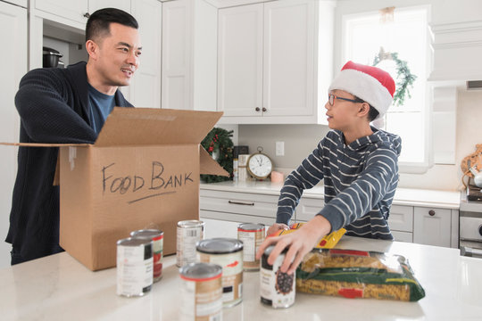 Father and son preparing box for food bank