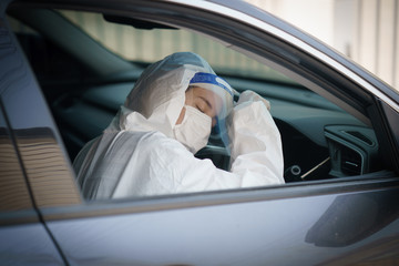Woman driver with gloves,protective hazmat suit, face shield and mask..corona virus or Covid-19 protection.