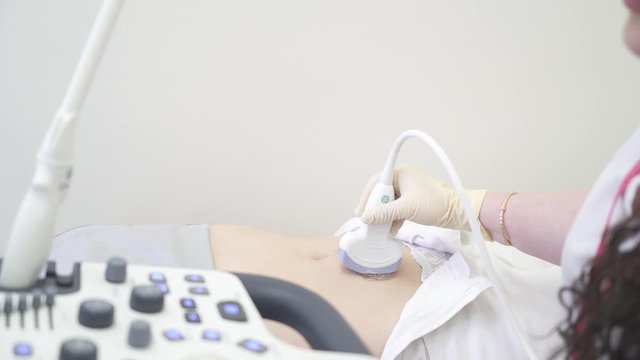 Frame for post-production. Hand of a doctor in a glove makes an ultrasound procedure to a patient. Belly of a girl.