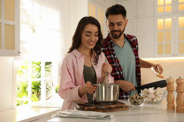 Lovely young couple cooking together in kitchen