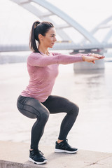 Sportswoman squatting, doing some excersize.