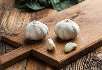 Garlic on chopping board on wooden background.