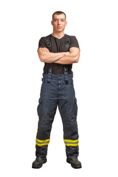Young firefighter with folded arms wearing black t-shirt and fireproof pants with suspenders isolated