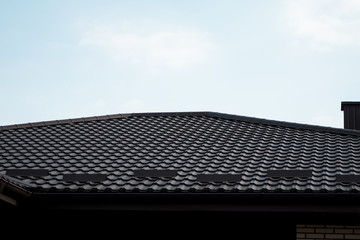 Brown metal tile roof. Roof metal sheets. Modern types of roofing materials. Roof of the house, metal roof tile against the blue sky. Building.