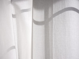 Soft morning shadows cast by the rising sun on soft linen curtains in an american home