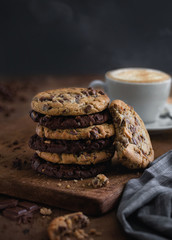 stack of chocolate and oatmeal cookies with a cup of coffee on a wooden plate