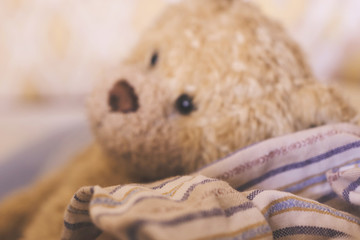Stay home. Teddy bear in defocus, with some warm pajamas. Begcound texture home comfort.