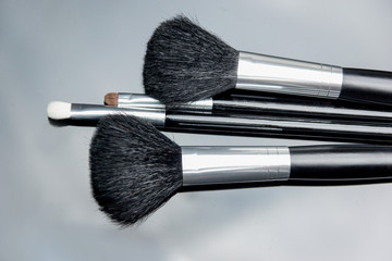 make up brushes lying on black glass table. photo with selectiv focus, low key photo