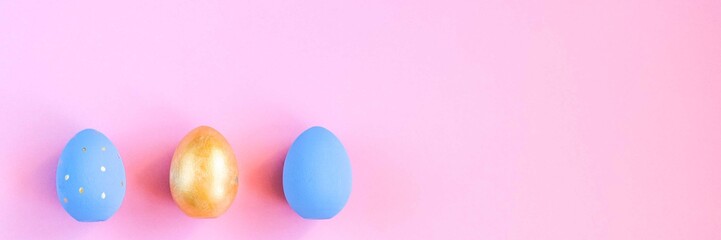 Gold and blue easter eggs on pink background.