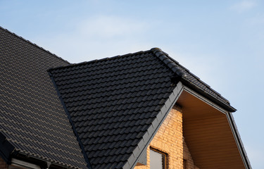 Brown metal tile roof. Roof metal sheets. Modern types of roofing materials. Roof of the house, metal roof tile against the blue sky. Building.