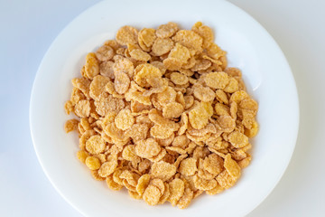 Their flakes are poured a lot. The plate is white. Close-up. The background is not uniform