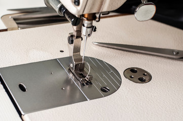 Needle and foot of sewing machine closeup as manufactoring background