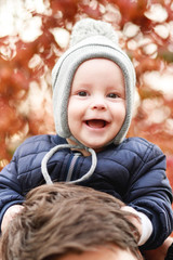 a small son sits on the shoulders of a young father