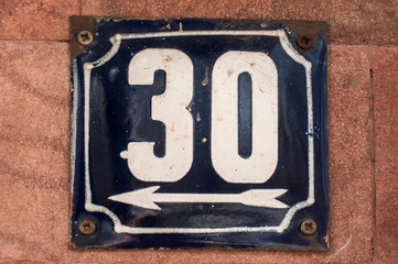 Weathered grunge square metal enameled plate of number of street address with number 30 closeup