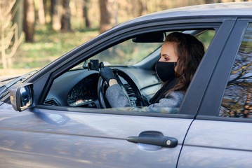 Woman in the city. Person in a mask. Coronavirus theme. Woman by the car.