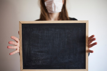 masked woman holding a chalk board/message during an epidemic/copy space