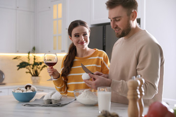 Lovely young couple cooking dough together in kitchen