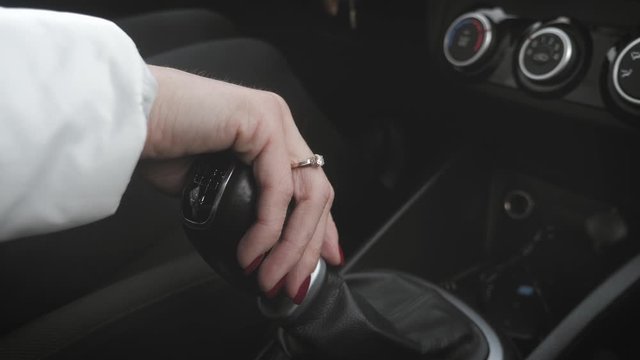 Female hand on automatic transmission car lever. Young woman changing gears in car. Manual transmission.
