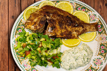 fried fish with fresh salad and lemon.