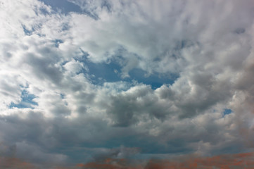Fototapeta premium The sky at sunset. Cumulus clouds lit by the rays of the setting sun.