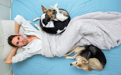 Shepherd dog lying with male on bed at home