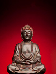 A small replica statue of The Buddha with a red background
