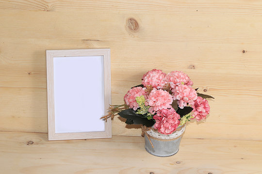 Potted flowers and frame for text on a wooden background, home office. Creative modern bouquet, minimal holiday concept. Greeting card for Women's Day or Mother's Day, Happy Birthday,