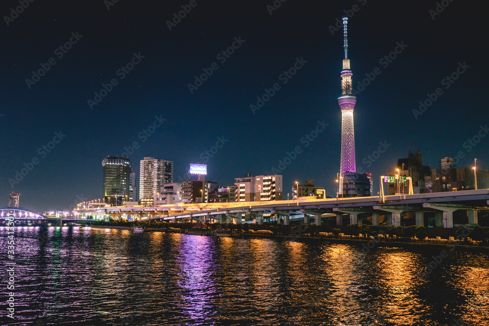 Wall mural tokyo cityscape by night, with sumida river with reflections in front and tokyo skytree tower with l