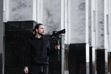 Young Professional videographer holding professional camera on 3-axis gimbal stabilizer. Pro...